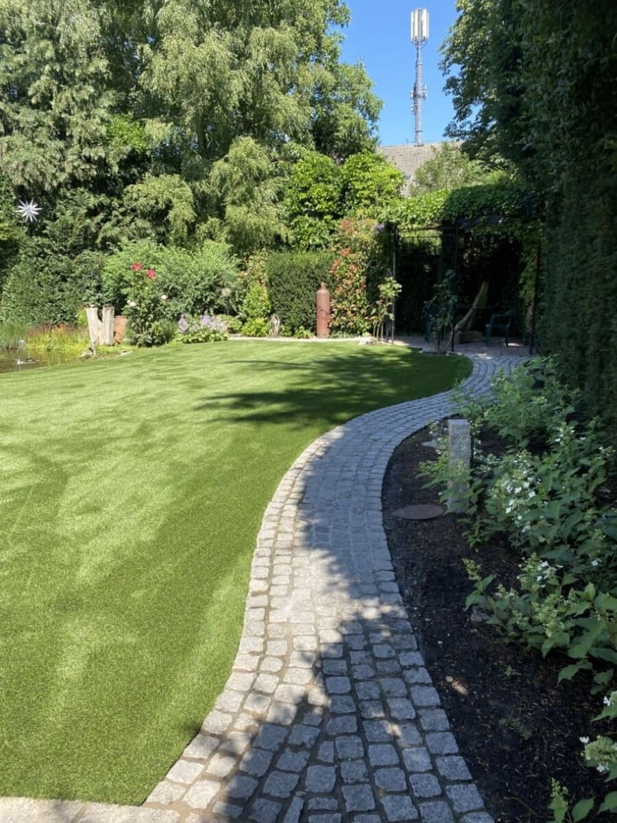 Ein Garten mit Kunstrasen und üppiger Vegetation solera